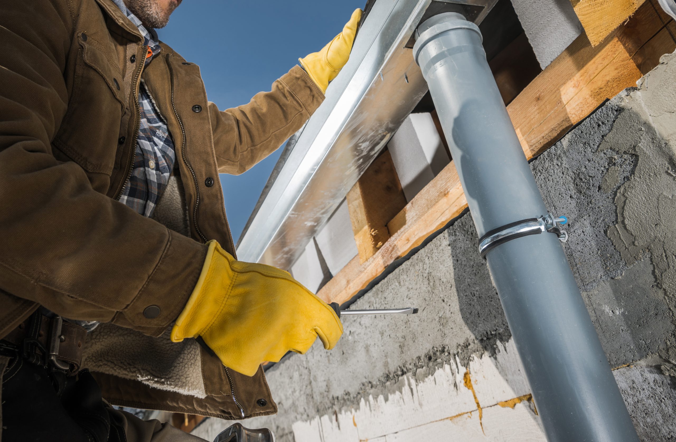 Worker Finishing Installation of Eaves Roof Gutters